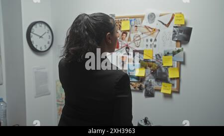 Eine junge Frau ermittelt eine Kriminalbehörde mit Beweisen im Büro einer Polizeibehörde. Stockfoto