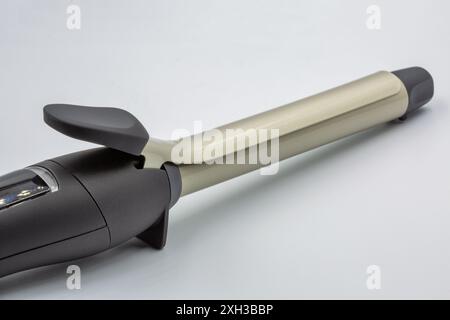 Elegantes Lockenbügeleisen für professionelles Styling mit modernem Design und fortschrittlicher Heiztechnologie. Nahaufnahme auf weiß. Stockfoto