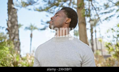 Beschaulicher afroamerikanischer Mann genießt im Stadtpark Ruhe im Freien. Stockfoto