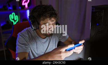 Hispanischer Mann, der nachts drinnen spielt, beleuchtet von bunten Neonlichtern in einem dunklen Raum. Stockfoto