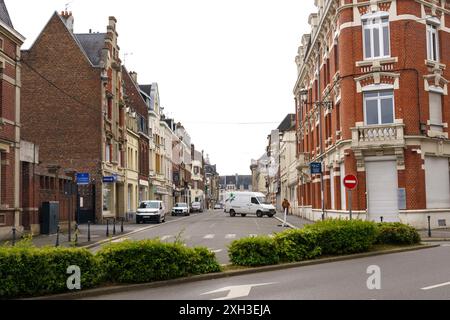 Cambrai, Frankreich - 21. Mai 2023: Eine Straße mit Backsteinhäusern in Cambrai, Frankreich, mit einem weißen Van, der in der Mitte der Straße geparkt ist. Stockfoto