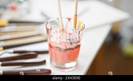 Ein Nahfoto eines Glases mit in Wasser getauchten Pinseln, das den künstlerischen Prozess in einer kreativen Umgebung zeigt. Stockfoto