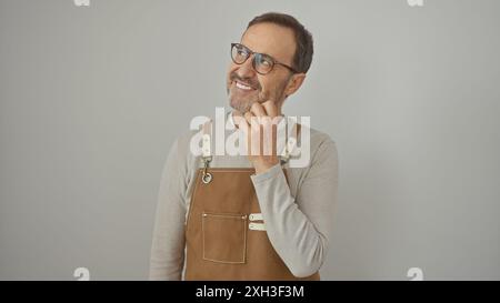 Bärtiger Mann mittleren Alters in Schürze, der vor weißem Hintergrund lächelt Stockfoto