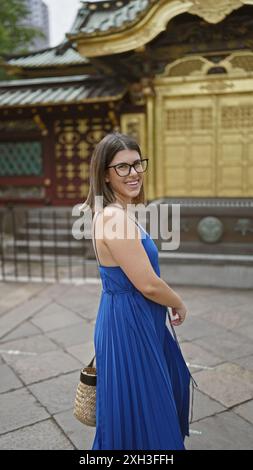 Schöne hispanische Frau mit Brille, die sich fröhlich in ihrem Kleid dreht, um den Tempel des ueno Parks in tokio. Ihr lebendiger Geist tanzt im urbanen Settin Stockfoto