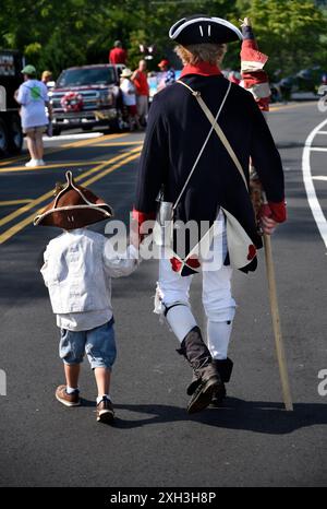 Ein Mann und sein Sohn, gekleidet in nachgebildeter Militärkleidung des 18. Jahrhunderts, nehmen an einer Parade am 4. Juli in Hendersonville, NC, Teil. Stockfoto