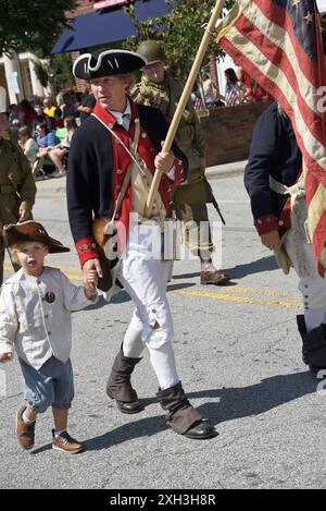 Ein Mann und sein Sohn, gekleidet in nachgebildeter Militärkleidung des 18. Jahrhunderts, nehmen an einer Parade am 4. Juli in Hendersonville, NC, Teil. Stockfoto