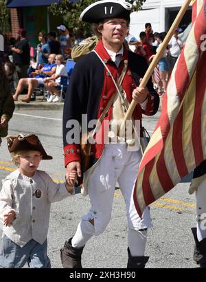 Ein Mann und sein Sohn, gekleidet in nachgebildeter Militärkleidung des 18. Jahrhunderts, nehmen an einer Parade am 4. Juli in Hendersonville, NC, Teil. Stockfoto