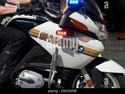 Ein Beamter des Henderson County Sheriff's Department auf einem Motorrad patrouilliert die Straße vor dem Beginn einer Parade am 4. Juli in North Carolina. Stockfoto