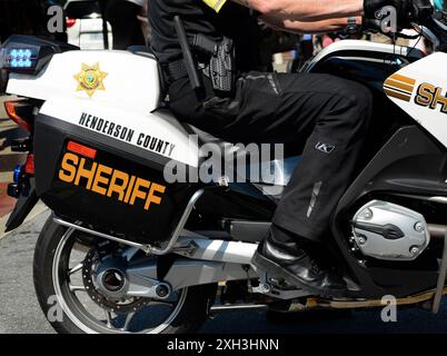 Ein Beamter des Henderson County Sheriff's Department auf einem Motorrad patrouilliert die Straße vor dem Beginn einer Parade am 4. Juli in North Carolina. Stockfoto