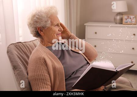 Leiden an Amnesie. Seniorin mit Buch zu Hause. Seite wird aufgelöst Stockfoto