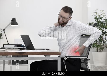 Mann mit Rückenschmerzen aufgrund schlechter Körperhaltung am Arbeitsplatz Stockfoto