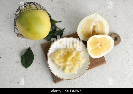 Teller und Korb mit frischen Pomelo-Früchten auf weißem Hintergrund Stockfoto