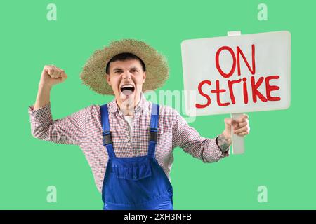 Protest gegen männlichen Landwirt, der ein Plakat mit STREIKTEXT vor grünem Hintergrund hält Stockfoto