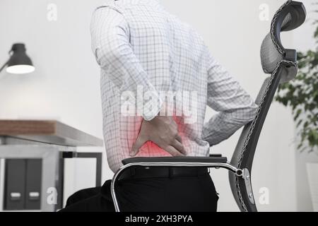 Mann mit Rückenschmerzen aufgrund schlechter Körperhaltung am Arbeitsplatz Stockfoto