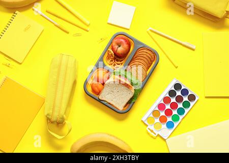 Schulbedarf, Lunchbox mit Sandwich und Aprikose auf gelbem Hintergrund. Draufsicht Stockfoto