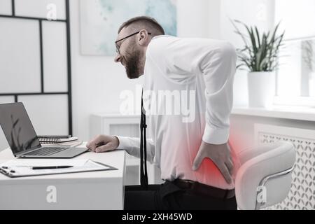 Mann mit Rückenschmerzen aufgrund schlechter Körperhaltung am Arbeitsplatz Stockfoto