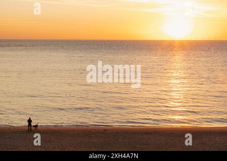 England, Kent, Kingsgate Bay, man and Dog on Beach at Sunrise Stockfoto