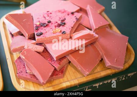 Holztablett mit magentafarbener Schokolade auf einem Tisch bei der Veranstaltung Stockfoto