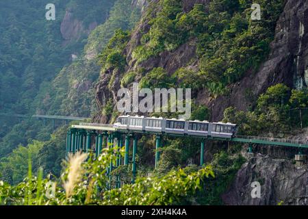 (240712) -- PEKING, 12. Juli 2024 (Xinhua) -- ein elektrischer Triebzug (EMU) fährt im Dajue Mountain Scenic Area in der ostchinesischen Provinz Jiangxi, 11. Juli 2024. Eine Reihe von 30 elektrischen Triebzügen (EMU), die Teil des sogenannten „Mountain Area Elevated Monorail Sightseeing Trains and Track System“ sind, wurden am Donnerstag in das Dajue Mountain Scenic Area im Zixi County, ostchinesischer Provinz Jiangxi, geliefert. Mehr als ein Drittel der 11,8 km langen Wanderroute verläuft entlang einer Klippe und die Züge „hängen“ Besucher in einer Höhe zwischen 850 und 1.150 Metern in die Luft. ich Stockfoto