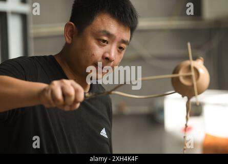 (240712) -- PEKING, 12. Juli 2024 (Xinhua) -- Xie Zhenwei überträgt Glasur auf ein Porzellangeschirr in einem Ofen in der Gemeinde Shabu, Huangyan von Taizhou, ostchinesische Provinz Zhejiang, 11. Juli 2024. Die Shabu-Öfen stammen aus der Tang-Dynastie (618–907) und blühten in der Nördlichen Song-Dynastie (960–1127) und gelten als Übergangsöfen während der Entwicklung der südlichen Seladonindustrie von Yue-Öfen zu Longquan-Öfen. Xie Zhenwei, ein junger Porzellanhandwerker und gebürtiger aus der Gemeinde Shabu, hat sich bemüht, die Seladonwaren im Stil der Shabu-Öfen zu reproduzieren, was Charact ist Stockfoto