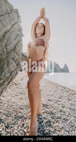 Frau in Pink Bikini posiert auf einem Kieselstrand Stockfoto