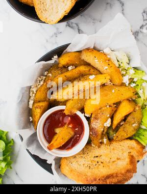 Leckere gebratene Kartoffeln mit aromatischen Gewürzen auf handwerklichem Papier, vor Marmorhintergrund. Eine perfekte Idee für ein Abendessen. Stockfoto