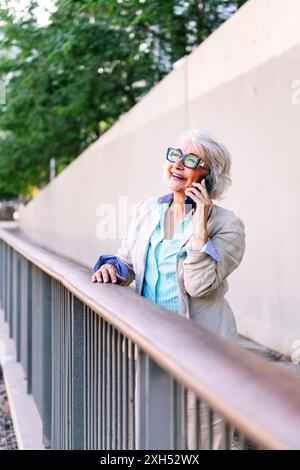 Reife Frau lacht glücklich, während sie telefoniert Stockfoto