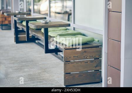 Ein Café im Freien in der Stadt. Tische mit Sofas und auf der Straße vor dem Hintergrund von Fenstern. Der Bodenbelag besteht aus Beton auf dem Boden mit Platz zum Kopieren. Hochwertige Fotos Stockfoto