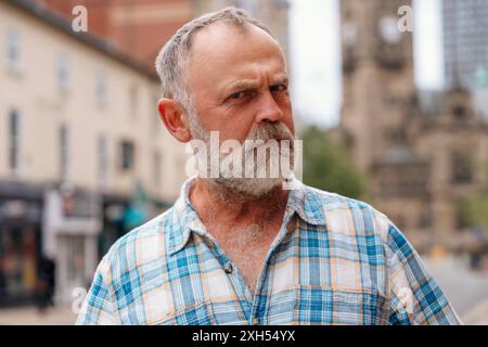 Ein ungläubiger, runzelnder, überraschter bärtiger Mann in einem karierten Hemd schaut in eine Kamera in der Stadt Stockfoto