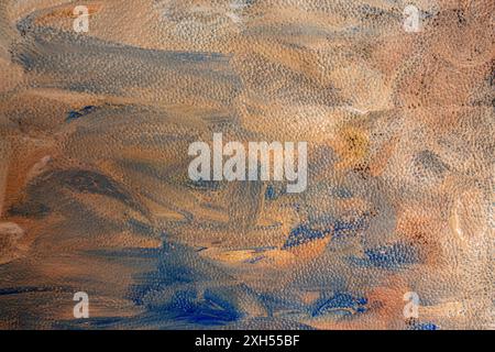 Gewellte Acrylfarbe, blaue, orange und beige Flecken auf Lederstruktur Stockfoto