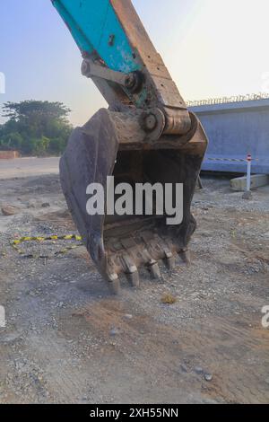 Der Löffel ist mit Schmutz und Ablagerungen gefüllt. Eine große, schmutzige und rostige Baumaschine mit einer großen Schaufel an der Vorderseite. Stockfoto