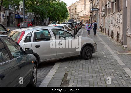 Wie man kein Auto parkt, hat der Fahrer sein Fahrzeug halb auf der Straße und halb auf dem Bürgersteig in dieser Belgrader Straße gelassen. Mai 2024 Stockfoto