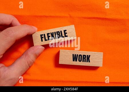 Flexible Arbeitsbotschaft auf Holzblöcken mit orangefarbenem Hintergrund. Konzeptionelles flexibles Arbeitssymbol. Kopierbereich. Stockfoto