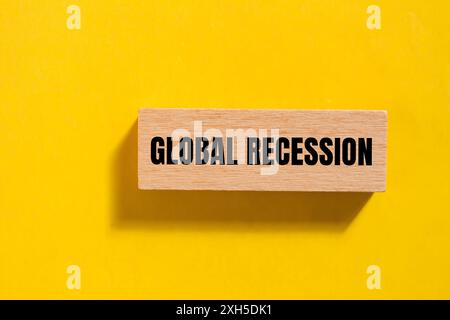 Globale Rezessionsnachricht auf einem einzelnen Holzblock mit gelbem Hintergrund. Konzeptionelles globales Rezessionssymbol. Kopierbereich. Stockfoto