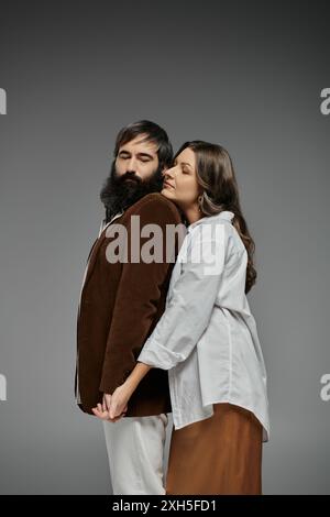Ein liebevolles Paar in stilvoller Kleidung, das sich mit den Armen umeinander posiert. Stockfoto