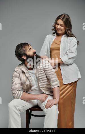 Ein Mann und eine Frau in stilvollen Outfits posieren zusammen und blicken sich gegenseitig mit liebevollen Blicken in die Augen. Stockfoto