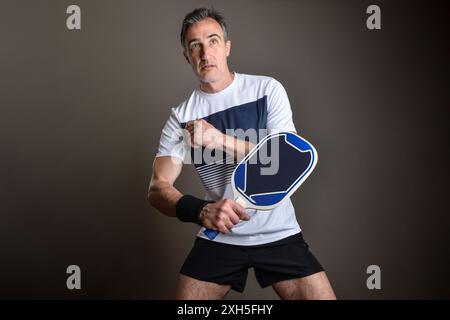 Porträt eines geballten Pickleball-Spielers, der auf einen Ball wartet, auf grauem isoliertem Hintergrund. Stockfoto