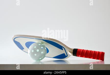 Hintergrund des Pickleball-Paddels auf dem Ball reflektiert auf weißem Tisch und weißem isolierten Hintergrund. Vorderansicht. Stockfoto