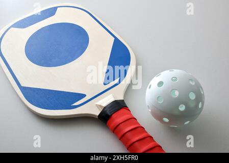 Detail des Pickleball-Schlägers und einer weißen Kugel isoliert auf weißem Tisch. Erhöhte Aussicht. Stockfoto