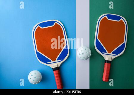 Blaue und orange Holzpaddel und ein weißer Ball auf dem Spielplatz. Draufsicht. Stockfoto