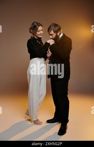 Ein liebevolles Paar in eleganter Kleidung, der Mann küsst die Frauenhand, während sie zärtlich lächelt. Stockfoto