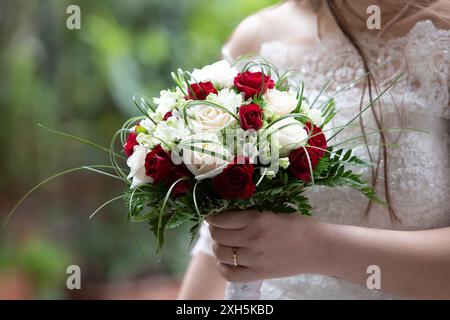 Braut mit einem weißen und roten Rosenstrauß an ihrem Hochzeitstag Stockfoto