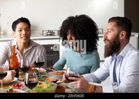 Eine vielfältige Gruppe von Freunden genießt köstliches Pasta-Abendessen mit Wein zu Hause Stockfoto