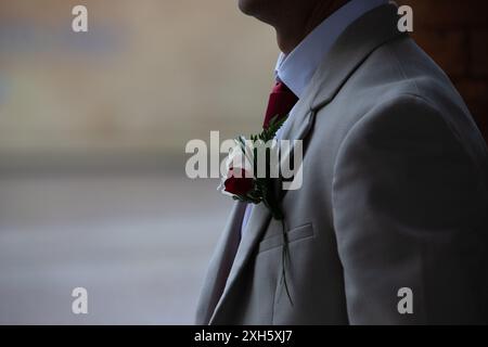 Der Bräutigam steht draußen an seinem Hochzeitstag und trägt eine Boutonniere am Revers seiner Anzugsjacke Stockfoto