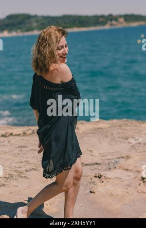 Happy woman in dress on sunny beach day Stockfoto