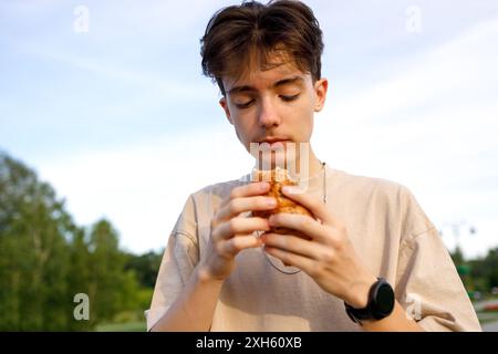 Young person eating sandwich outdoors Stockfoto