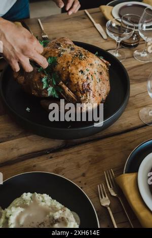 Person garnishing a roasted turkey on a dinner table. Stock Photo