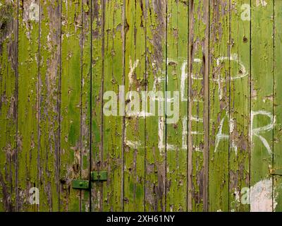 Weathered green wooden door with peeling paint and 'Keep Clear' sign Stockfoto