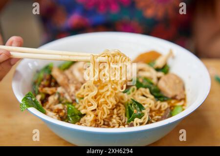 Midsection of woman eating instant noodles in a bowl Stock Photo