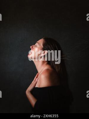 Woman with eyes closed and hair blowing on black background. Stock Photo